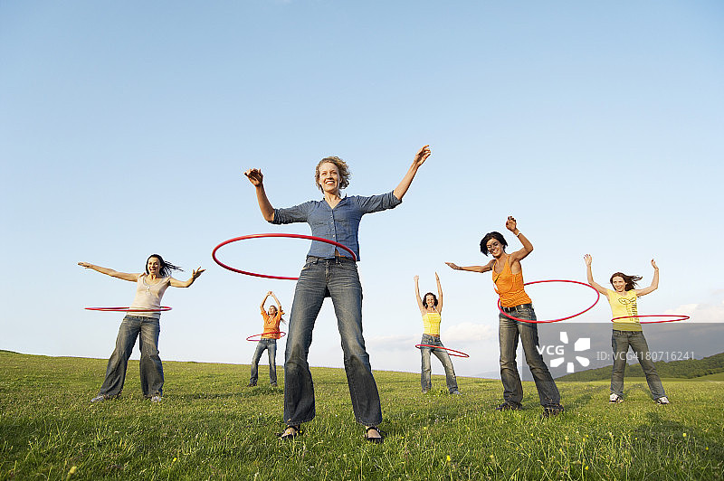 一群朋友在山地草地上玩呼啦圈（仰视）图片素材