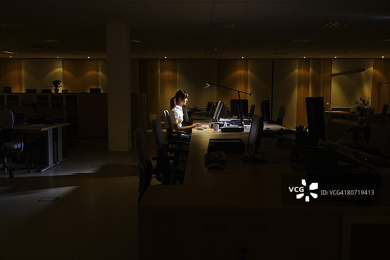 在黑暗办公室里工作的女人图片素材