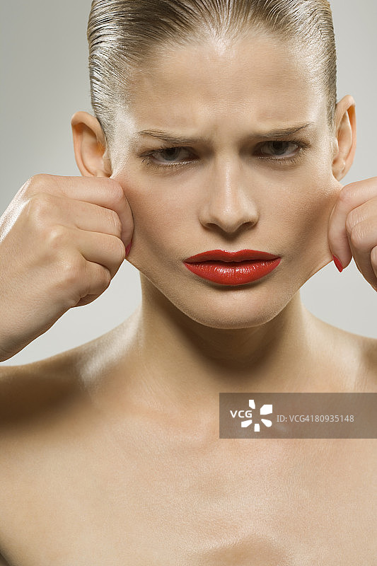 年轻女子用手拉扯脸颊图片素材