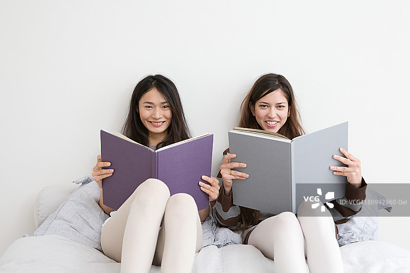 两名年轻女子手捧书籍的肖像图片素材
