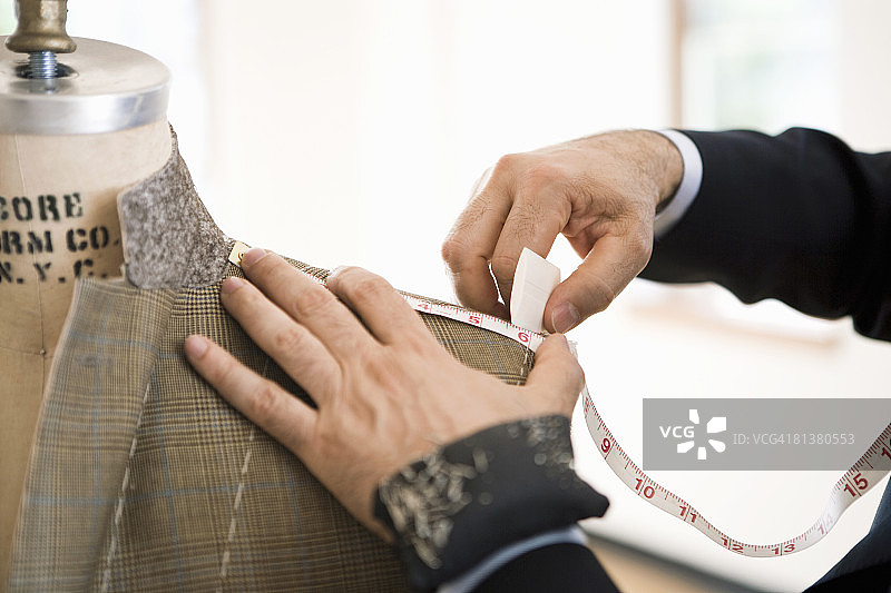 裁缝测量并用粉笔在夹克肩部做记号图片素材