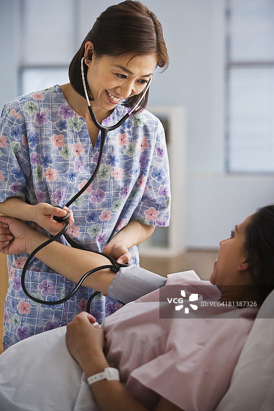 亚洲护士为西班牙裔女病人量血压图片素材