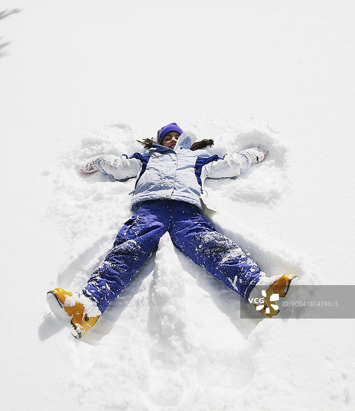 女孩在雪地里做雪天使，欢笑图片素材
