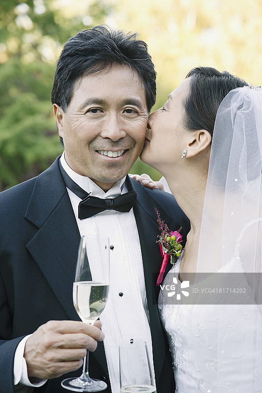 亚洲新娘亲吻新郎脸颊图片素材