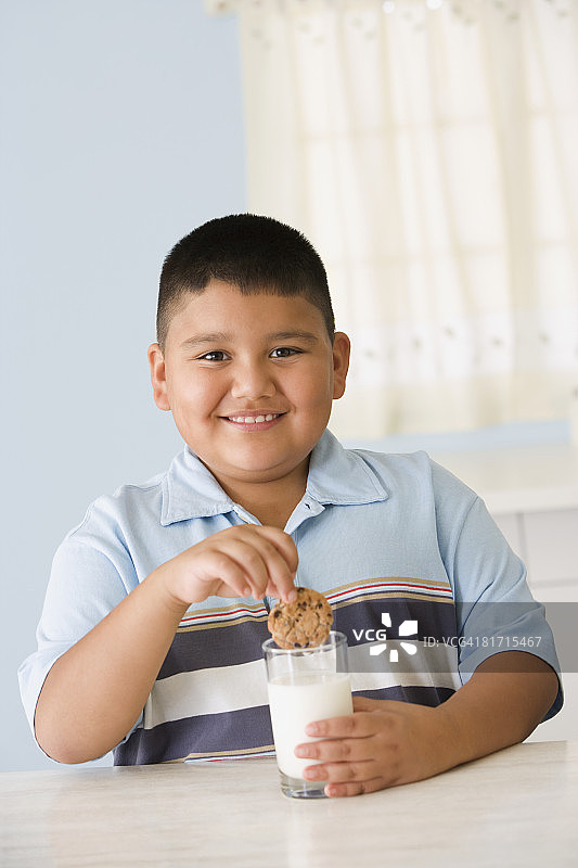 西班牙裔男孩将饼干浸在牛奶中图片素材