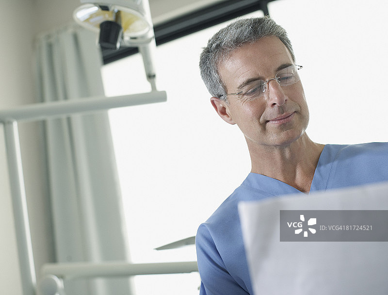 牙医站在诊室里查看图表图片素材