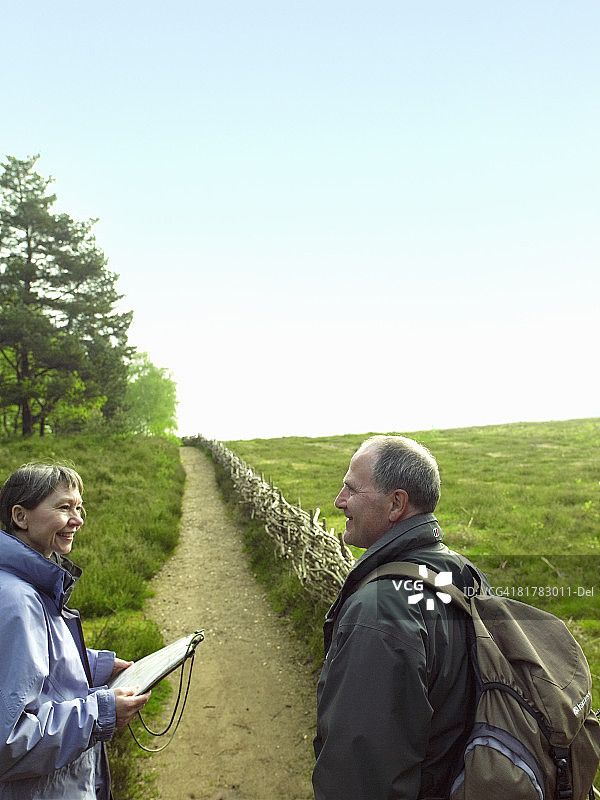 情侣在矮树篱笆小路上徒步旅行时停下来休息图片素材