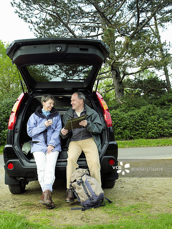 徒步后，情侣在车后座休息，看地图并享用茶点图片素材