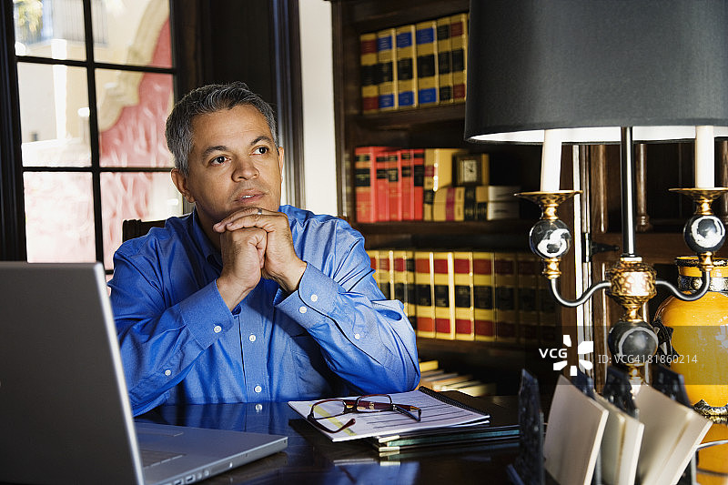 在办公桌前思考的西班牙裔男人图片素材