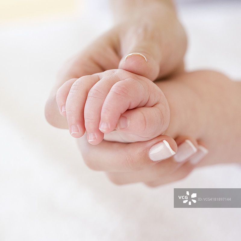 母亲握着婴儿的手的特写图片素材