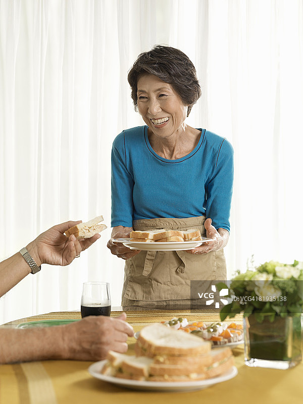一位拿着食物、面带微笑的老年妇女图片素材