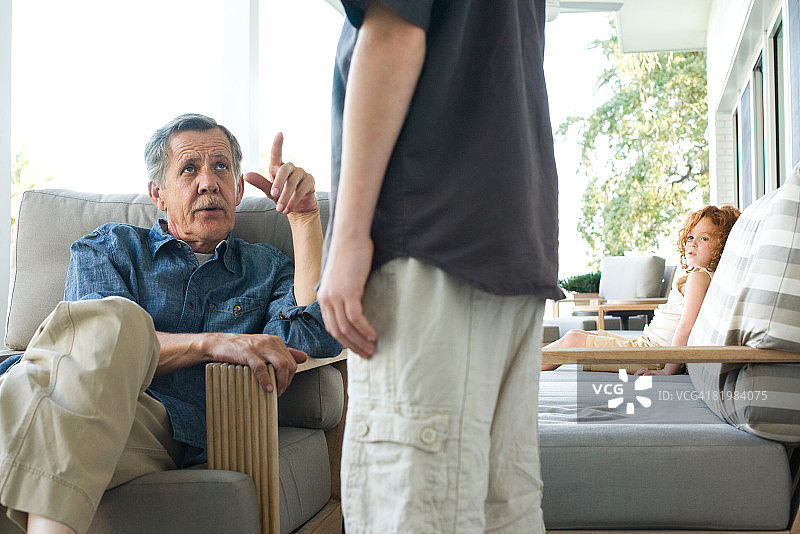 坐在椅子上，抬头看着孙子的年长男人（局部视角）图片素材