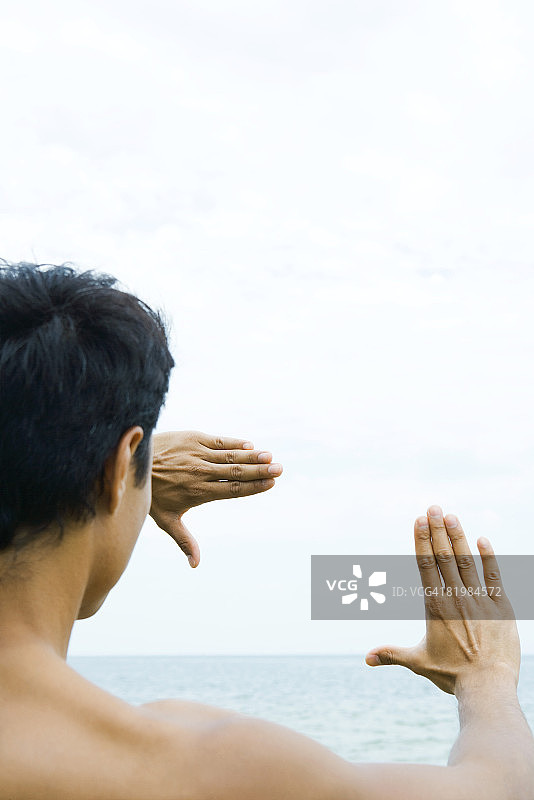 透过手指框架看海的男人（肩部视角）图片素材