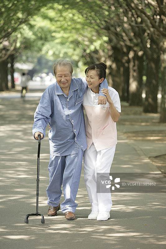 女护士帮助老年男人拄拐行走图片素材