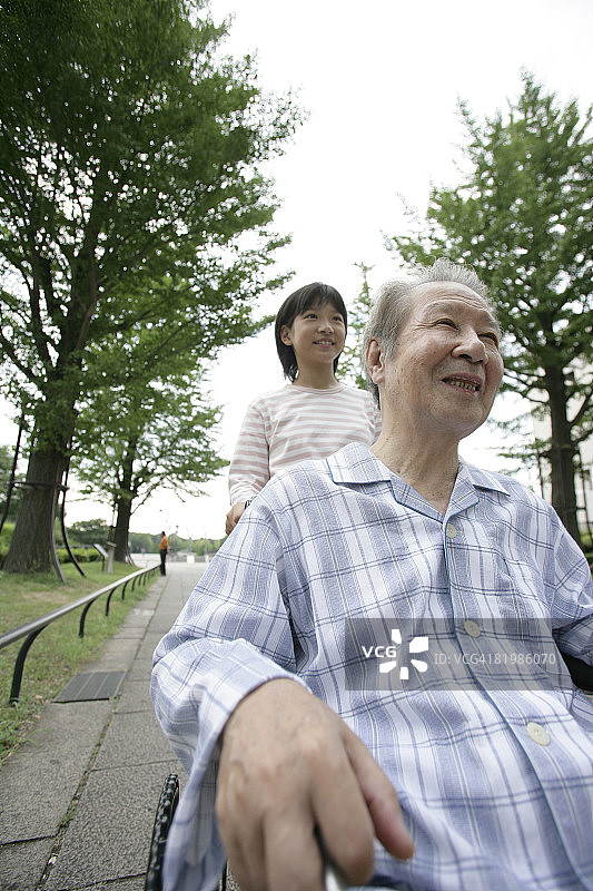 年轻女孩与坐轮椅的中年男人一起散步图片素材