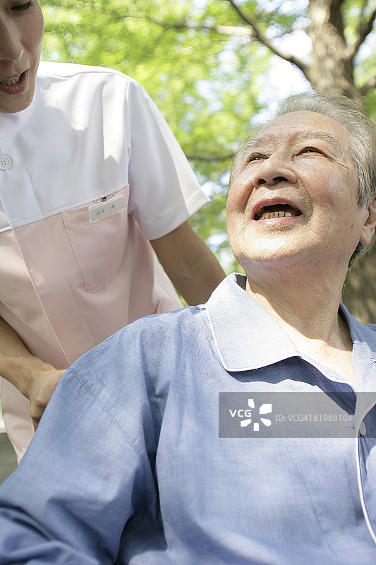 女护士与坐在轮椅上的中年男人散步图片素材