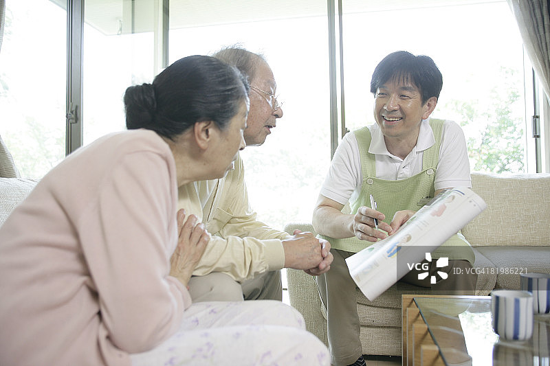 男子与中年夫妇交谈，手持文件图片素材