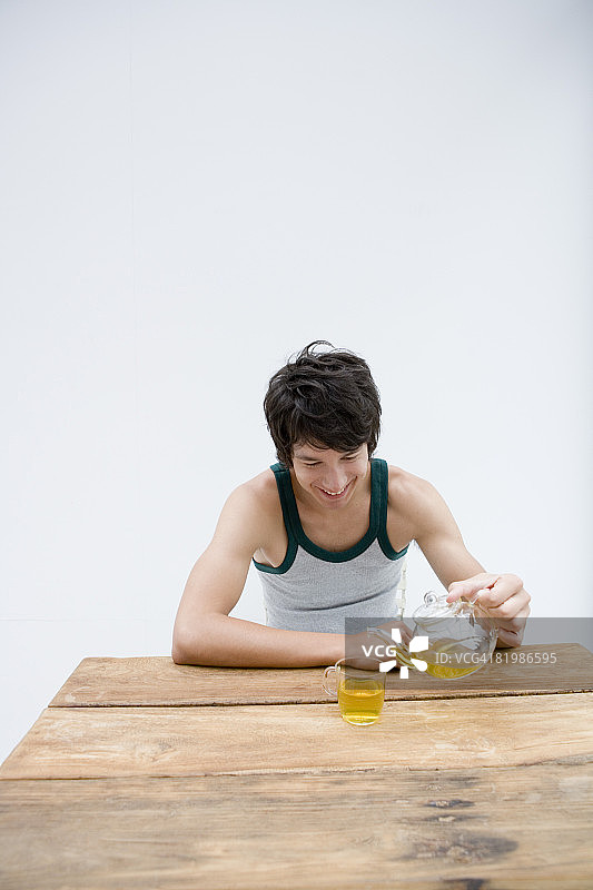 年轻男人微笑地坐着倒绿茶图片素材