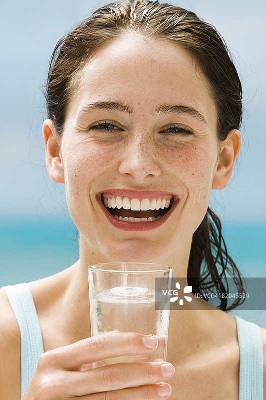 手持水杯微笑的年轻女人肖像图片素材