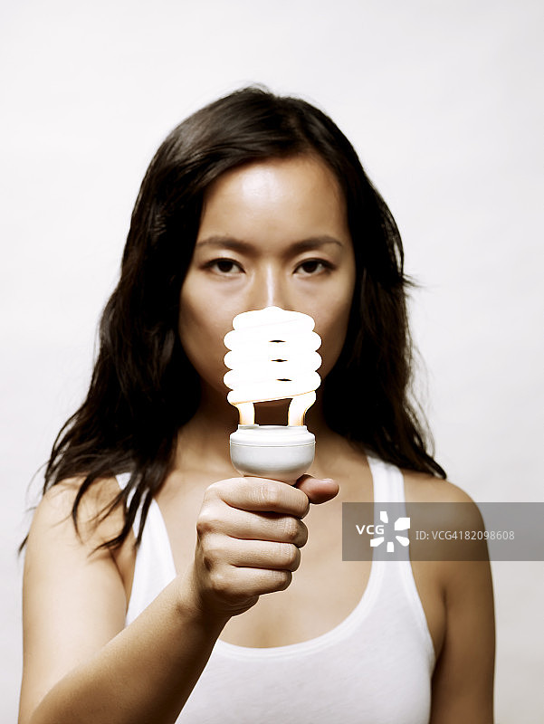 手持节能灯泡的年轻亚洲女性图片素材