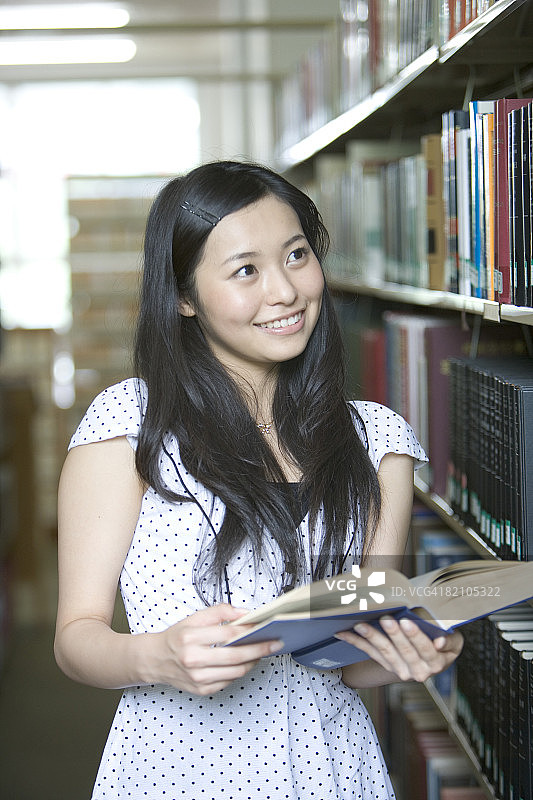 年轻女子在图书馆里拿着一本书图片素材