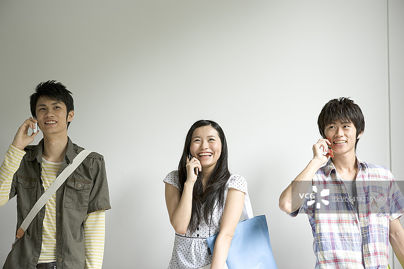 一位女学生和两位男学生在用手机交谈图片素材