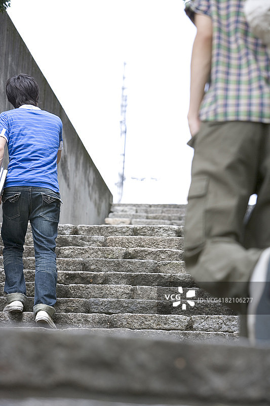 两位年轻男子走上楼梯，后视图图片素材
