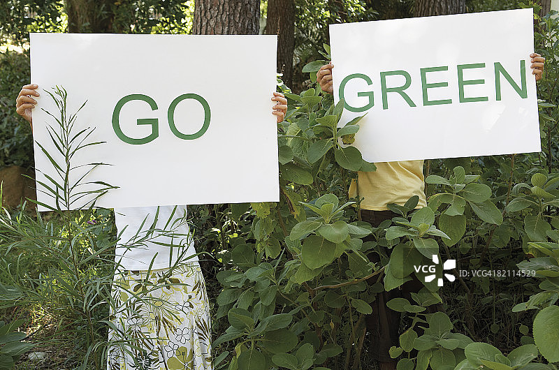 站在森林里举着“GO Green”标语的男人和女人图片素材
