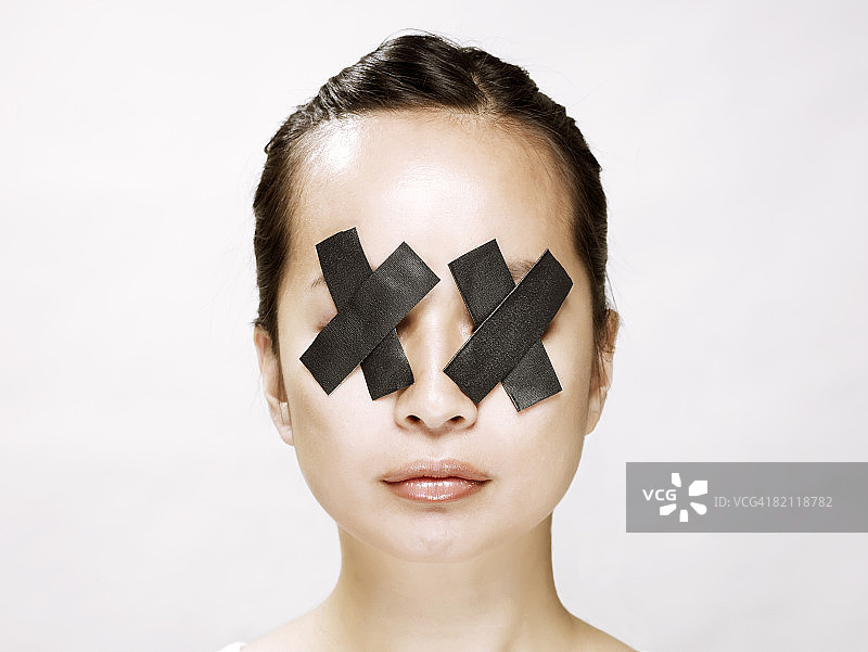 年轻亚洲女人眼睛蒙着黑胶带图片素材