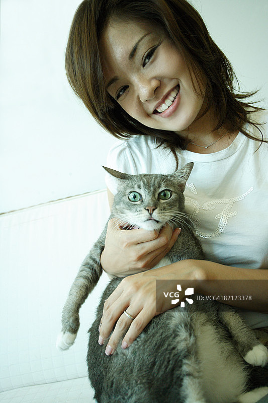 年轻女人抱着猫坐在沙发上肖像图片素材