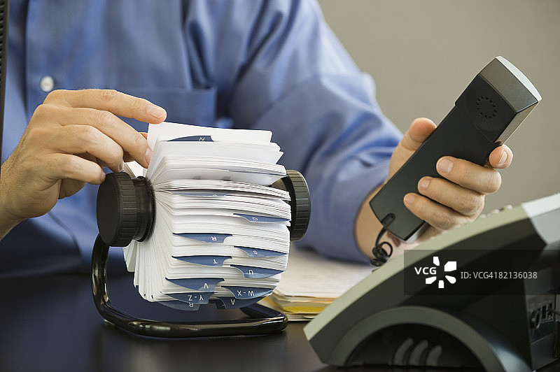 商务人士手持电话并查看卡片文件图片素材