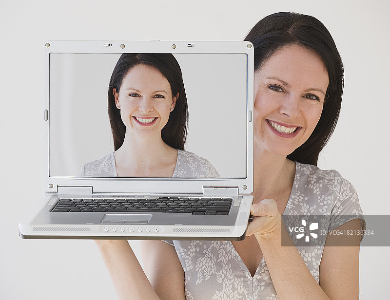 拿着笔记本电脑在脸旁的女人图片素材