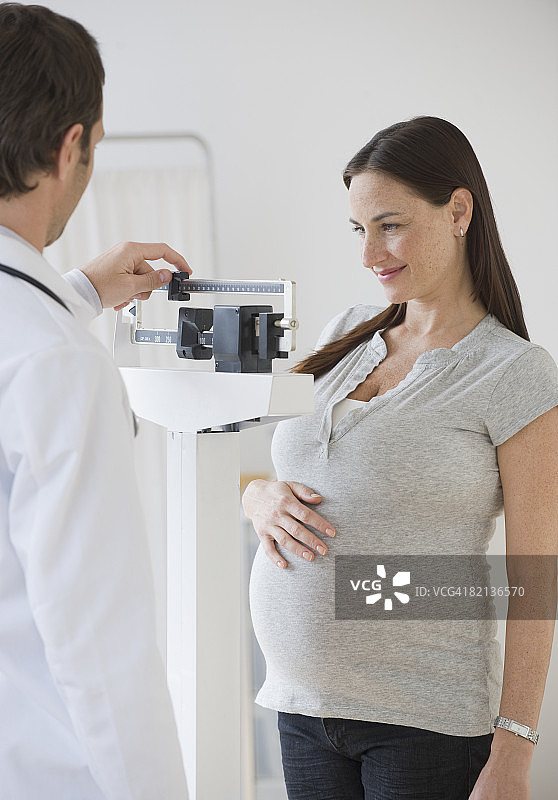 西班牙裔孕妇在医生办公室称体重图片素材