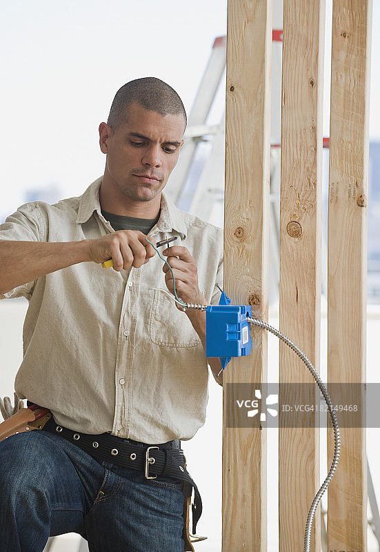 在新建建筑中工作的西班牙裔男电工图片素材