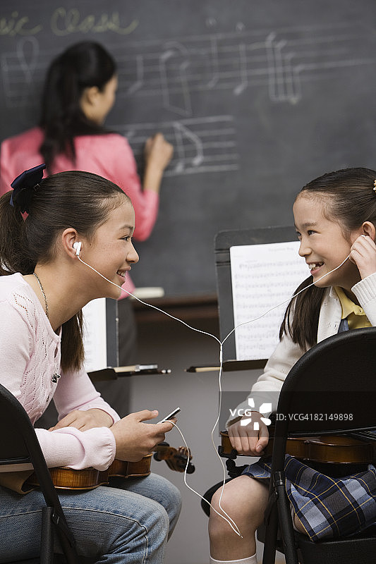 在音乐课上用MP3播放器听音乐的亚洲少女图片素材
