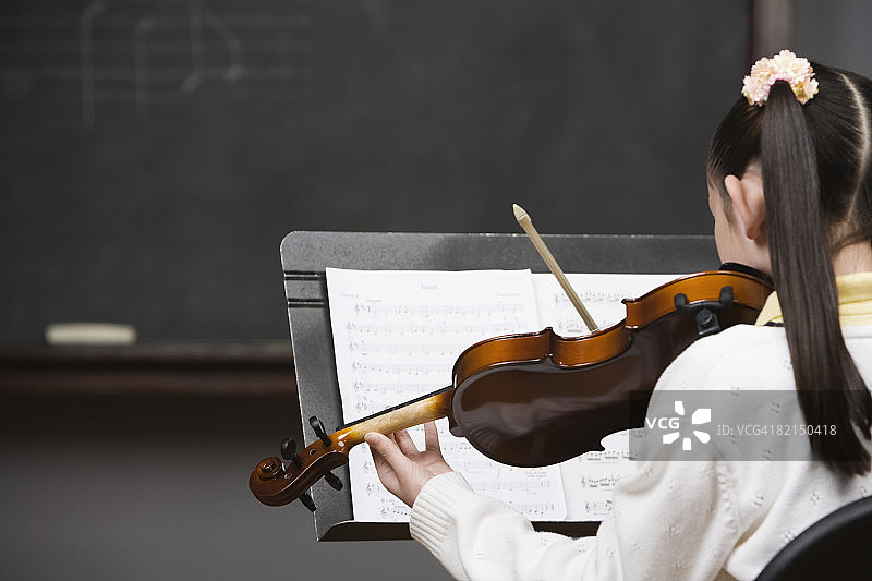在黑板前拉小提琴的亚洲女孩图片素材