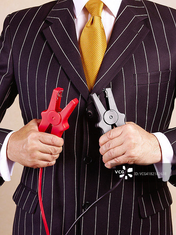 身穿细条纹西装的商人拿着汽车跨接电缆图片素材