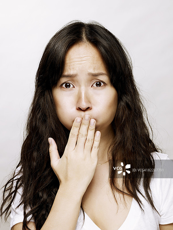 用手捂住嘴巴的亚洲年轻女性图片素材