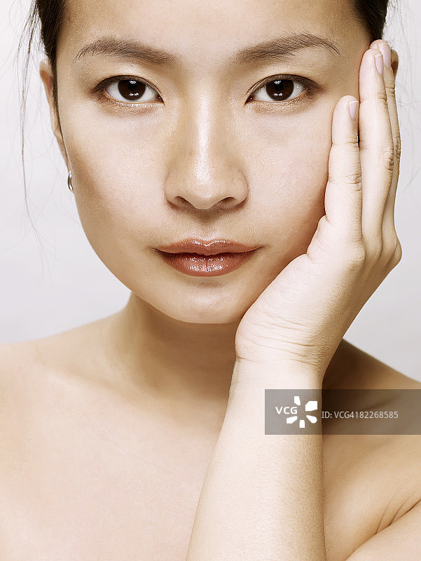 用手触摸脸部的年轻亚裔女人图片素材
