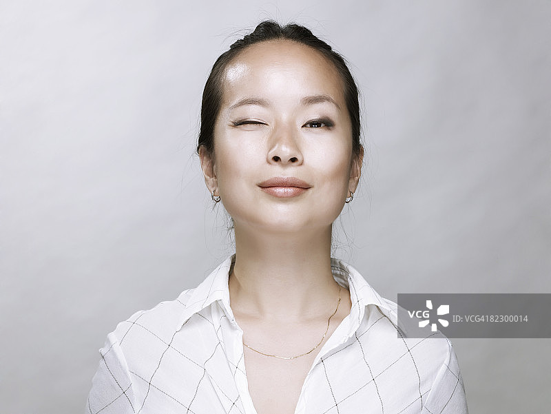 向镜头眨眼的年轻亚洲女性图片素材