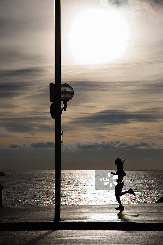 法国尼斯海边步道慢跑女子剪影图片素材