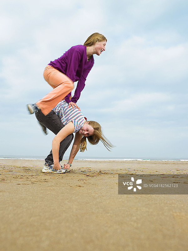 两名女子在沙滩上玩跳山羊图片素材