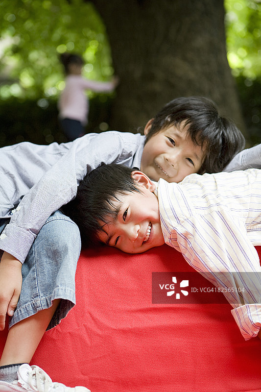两个男孩躺在花园里的红色沙发上图片素材