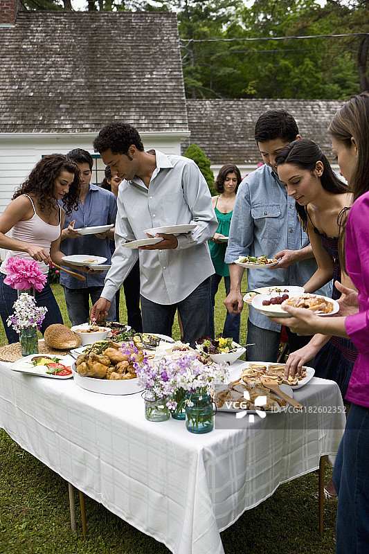 在乡村住宅参加户外花园派对的西班牙裔人图片素材