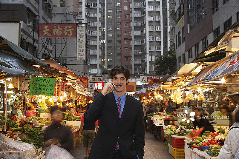 年轻的商人在街头市场用手机交谈图片素材