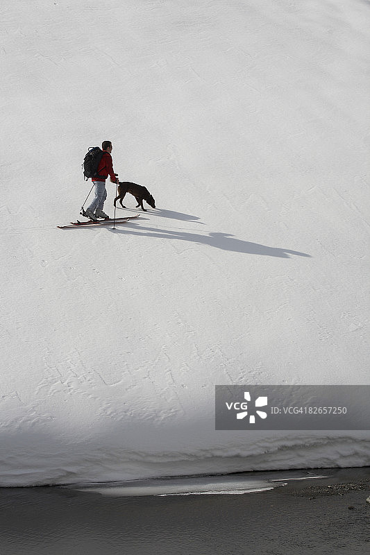 带狗的登山滑雪者图片素材