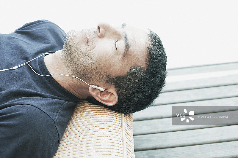 中年男人仰卧着听耳机图片素材