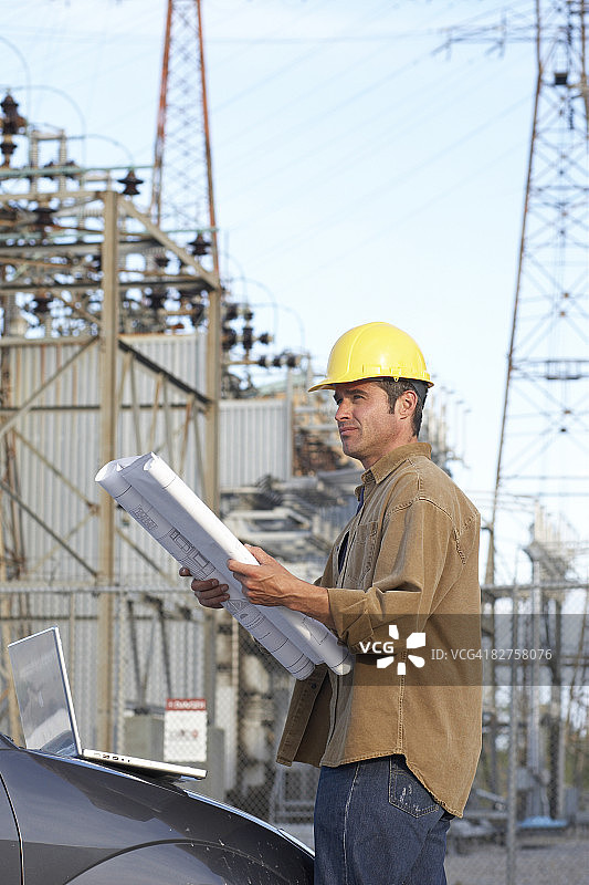 戴着建筑帽，拿着示意图的男人图片素材