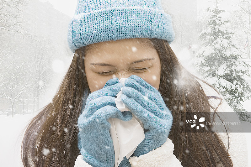 在雪中擤鼻子的西班牙裔女孩图片素材