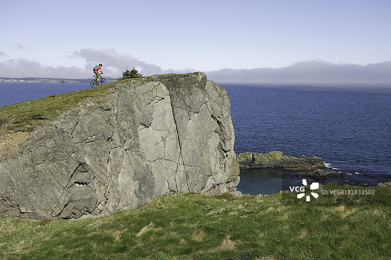 男人在海边悬崖骑山地自行车图片素材